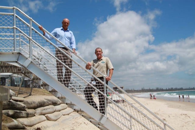 Testing out the new stairs to the beach at Kingscliff are Cudgen Headland Surf Life Saving Club president Adam Mills, left, and Tweed Shire Council's holiday-parks manager Richard Adams. The sandbag protection wall, under threat of damage from the number of people accessing the beach across it before the stairs were built, can be seen at the rear, in front of the Kingscliff Beach Holiday Park. 