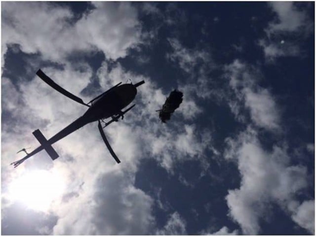 A police helicopter winches cannabis plants during raids. (supplied)