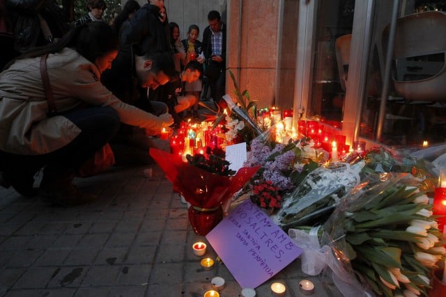 People place flowers and candles at the main gates of Barcelona’s Instituto Joan Fuster high school where earlier in the day a student burst into the school with a dagger and a crossbow on Monday April 20. A teacher died and four other people were injured in the attack.  EPA/Marta Perez