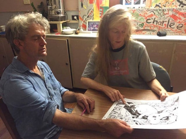 Artist Tim Roberts and Blackwall Range resident Suzie Whiteman work on a design for a fundraising t-shirt. (supplied)
