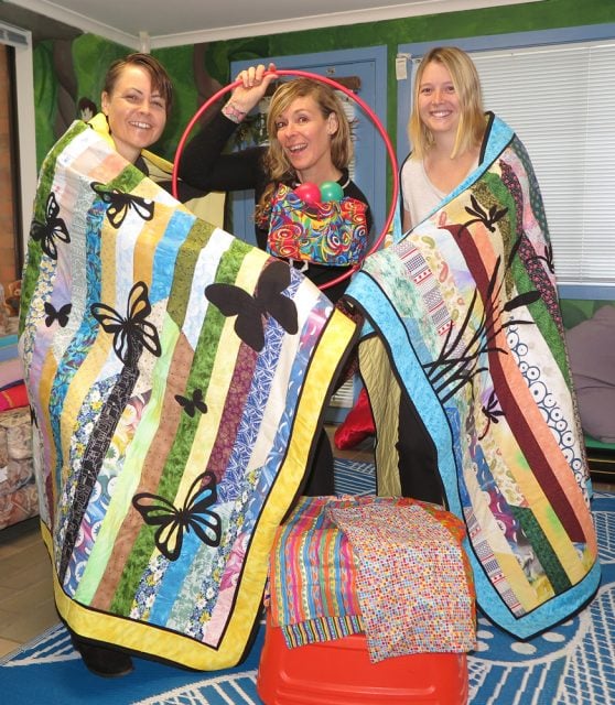  Social Workers Sharon Somerville, Louisa Harwood, and Social Worker student Jordan Stables show off the quilts and Circus Calming Kit bags donated by Ocean Shores Quilters. (Photo supplied)