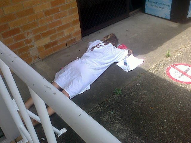 A woman lying on concrete outside Ballina Hospital on New Year's Day, when the hospital waiting room was full. Photo Maralyn Sweeney