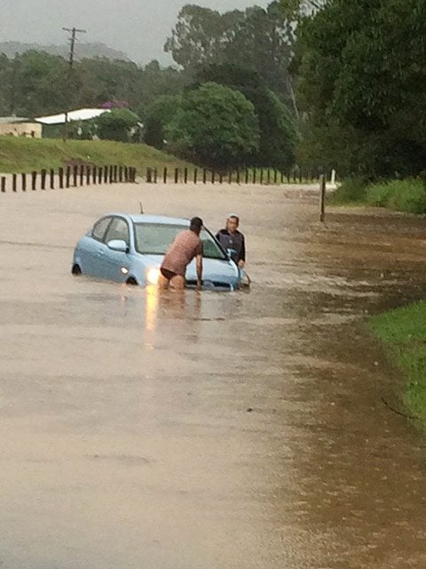 Two people trying to move a car stuck in water on Sherrys Bridge, Main Arm. The SES are again imploring people not to drive or walk through flooded causeways. Photo supplied